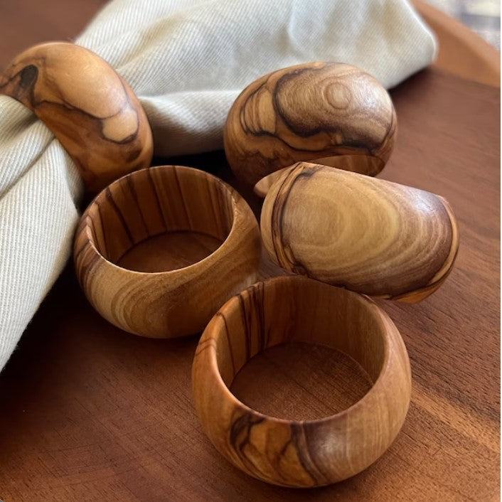 Five Olive Wood Napkin Rings On Table.